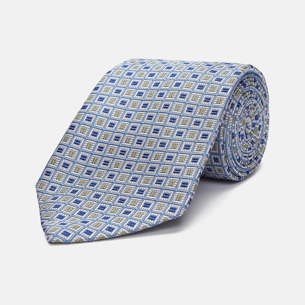 A Turnbull & Asser Blue and Yellow Geometric Silk Jacquard Tie is shown rolled up on a plain light background.