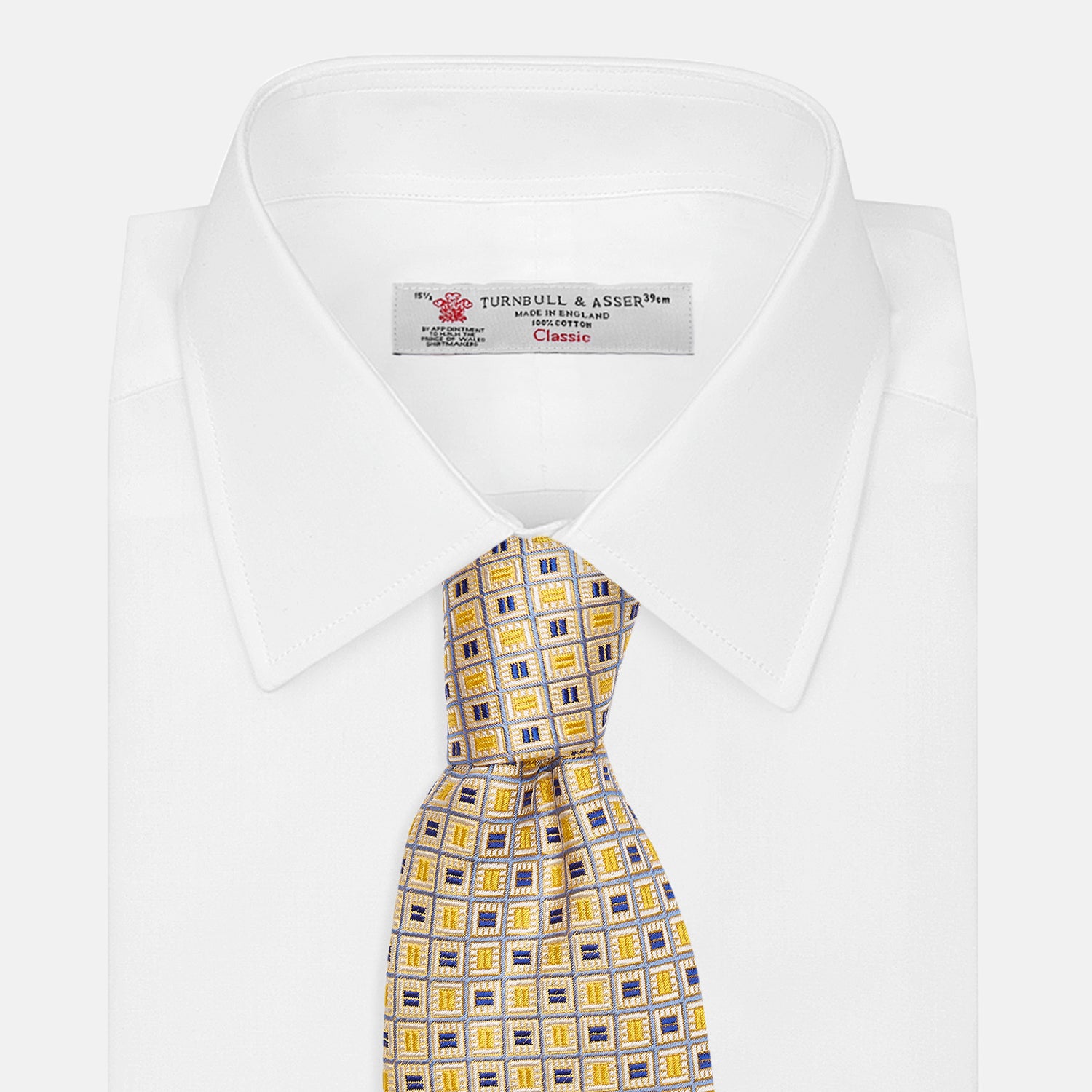 View 4 of product The Turnbull & Asser Yellow and Navy Geometric Silk Jacquard Tie features a striking square pattern on a light background, ideal for formal occasions, shown rolled up against a plain white surface.