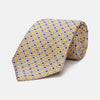 View 1 of product The Turnbull & Asser Yellow and Navy Geometric Silk Jacquard Tie features a striking square pattern on a light background, ideal for formal occasions, shown rolled up against a plain white surface.