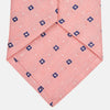 View 3 of product The Turnbull & Asser Pink Fine Square Slub Silk Tie features a pastel pink silk jacquard with blue and white geometric squares, shown rolled up on a plain white background.