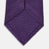 View 4 of product The Turnbull & Asser Purple Abstract Tonal Silk Jacquard Tie, featuring a textured geometric pattern, is shown rolled up against a white background—an ideal choice to elevate any formal outfit.