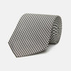 View 1 of product The Turnbull & Asser Fine Puppytooth Monochrome Silk Tie, in classic black and white, features a refined pattern and is shown rolled on a plain white background—ideal for enhancing any formal outfit.