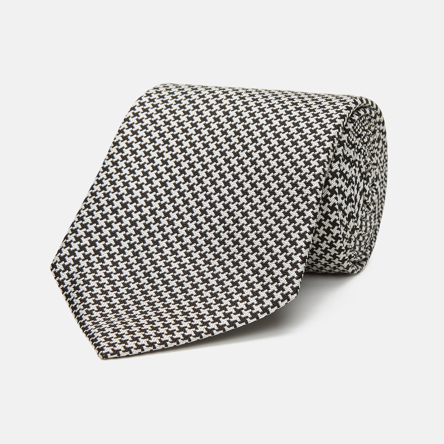 View 1 of product The Turnbull & Asser Fine Puppytooth Monochrome Silk Tie, in classic black and white, features a refined pattern and is shown rolled on a plain white background—ideal for enhancing any formal outfit.
