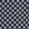 View 2 of product The Turnbull & Asser Indigo Graphic Floral Silk Jacquard Tie features a repeating pattern of light blue and white geometric shapes, shown rolled up on a plain white background.