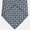 View 3 of product The Chambray Blue Graphic Floral Silk Jacquard Tie by Turnbull & Asser features a modern floral pattern in silk, shown rolled up against a plain white background.