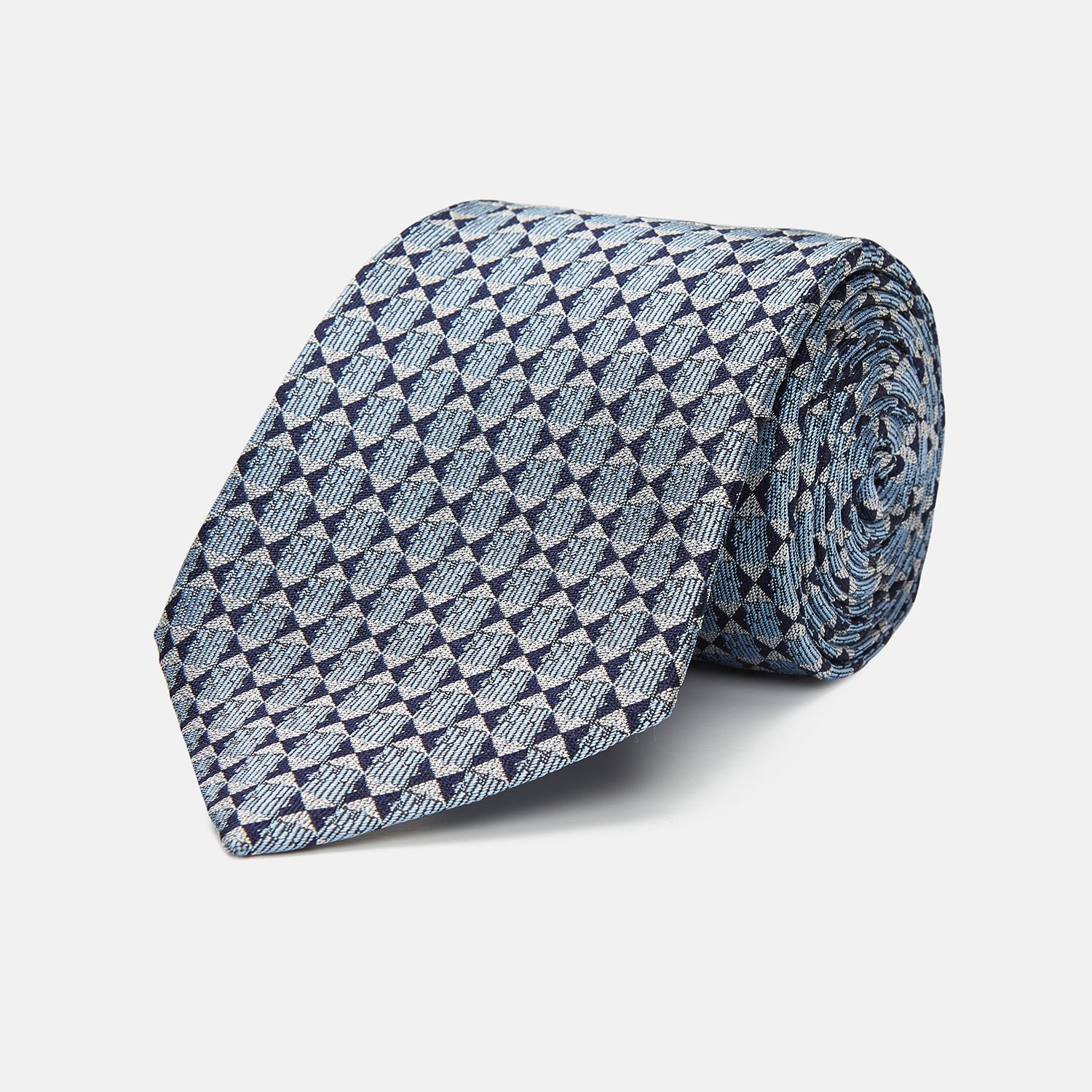 View 1 of product The Chambray Blue Graphic Floral Silk Jacquard Tie by Turnbull & Asser features a modern floral pattern in silk, shown rolled up against a plain white background.