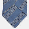 View 3 of product The Turnbull & Asser Dark Blue Baroque Stripe Silk Jacquard Tie, featuring elegant baroque stripes, is displayed rolled up on a white background.