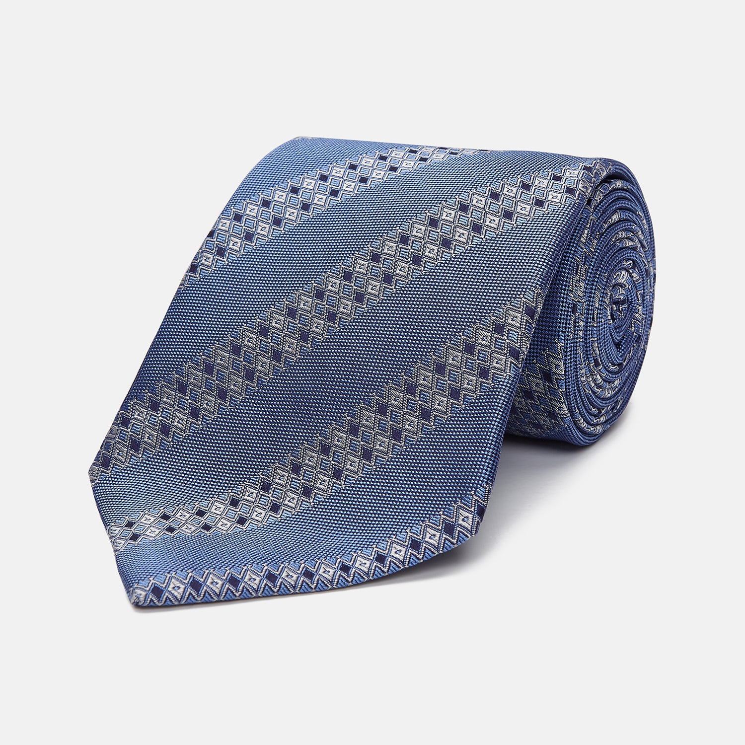 View 1 of product The Turnbull & Asser Dark Blue Baroque Stripe Silk Jacquard Tie, featuring elegant baroque stripes, is displayed rolled up on a white background.