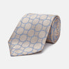 View 1 of product The Turnbull & Asser Toffee and Powder Blue Circle Jacquard Silk Tie, featuring an interlocking circular pattern, is rolled up and displayed on a plain white background.