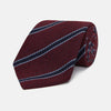 View 1 of product Turnbull & Asser’s Burgundy Stripe Wool and Silk Tie features diagonal navy and light blue stripes on a maroon background, shown rolled up against a plain light backdrop.