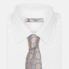 View 4 of product The Turnbull & Asser Toffee and Powder Blue Circle Jacquard Silk Tie, featuring an interlocking circular pattern, is rolled up and displayed on a plain white background.