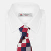 View 2 of product The Burgundy Checkerboard Silk Jacquard Tie by Turnbull & Asser features a bold autumnal pattern in red, navy blue, brown, gray, burgundy, and white squares, shown rolled on a plain white background.