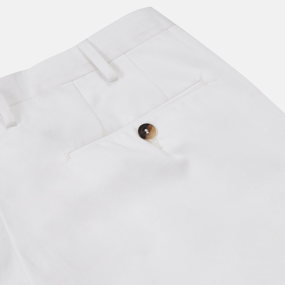 Turnbull & Asser’s White Cotton Pleated Trousers, a summer classic, are elegantly displayed against a crisp white backdrop.