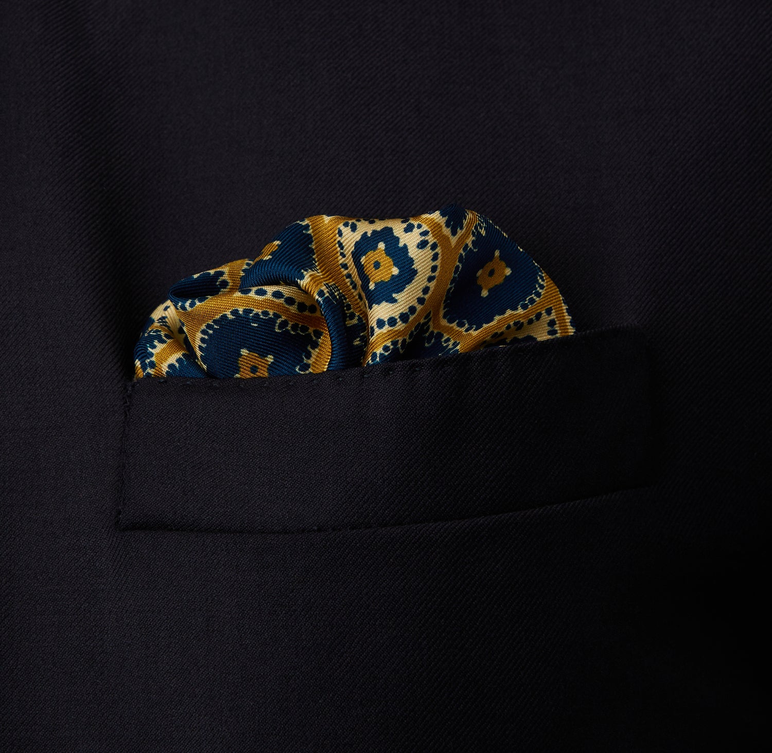 View 2 of product The Tan Medallion Print Silk Pocket Square by Turnbull & Asser features an elegant medallion geometric pattern in blue, white, and gold with central diamond shapes and a gold dotted border on luxurious silk.