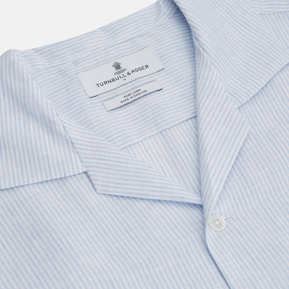 The Turnbull & Asser Blue Linen Stripe Holiday Fit Shirt features short sleeves, a revere collar, and single chest pocket, perfect for resort wear. Shown on a plain white background.