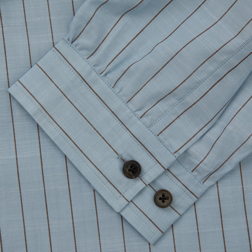 Turnbull & Asser's Pale Blue Stripe Cotton Holiday Fit Shirt features a revere collar, thin black pinstripes, single button cuff, chest pocket, and black buttons—crafted from Italian cotton and laid flat on a white background.