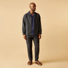 View 4 of product A man stands against a beige background, wearing a white t-shirt, Turnbull & Asser Navy Tailored Pinstriped Drawstring Trousers, and brown sandals. One hand is in his pocket as he looks straight at the camera.