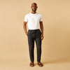 View 1 of product A man stands against a beige background, wearing a white t-shirt, Turnbull & Asser Navy Tailored Pinstriped Drawstring Trousers, and brown sandals. One hand is in his pocket as he looks straight at the camera.