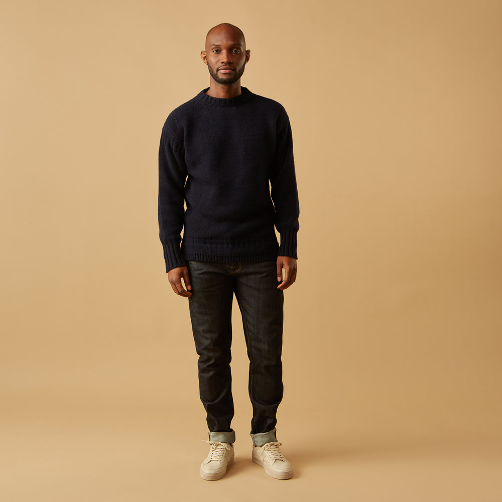 A man stands in the Turnbull & Asser Navy Lewis Guernsey Knitted Jumper.