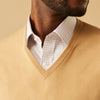 View 2 of product The Turnbull & Asser Camel V-Neck Merino Wool Jumper, with ribbed cuffs and a visible white neckline label, is neatly folded with one sleeve showing—an essential, versatile staple for any gentleman's wardrobe.