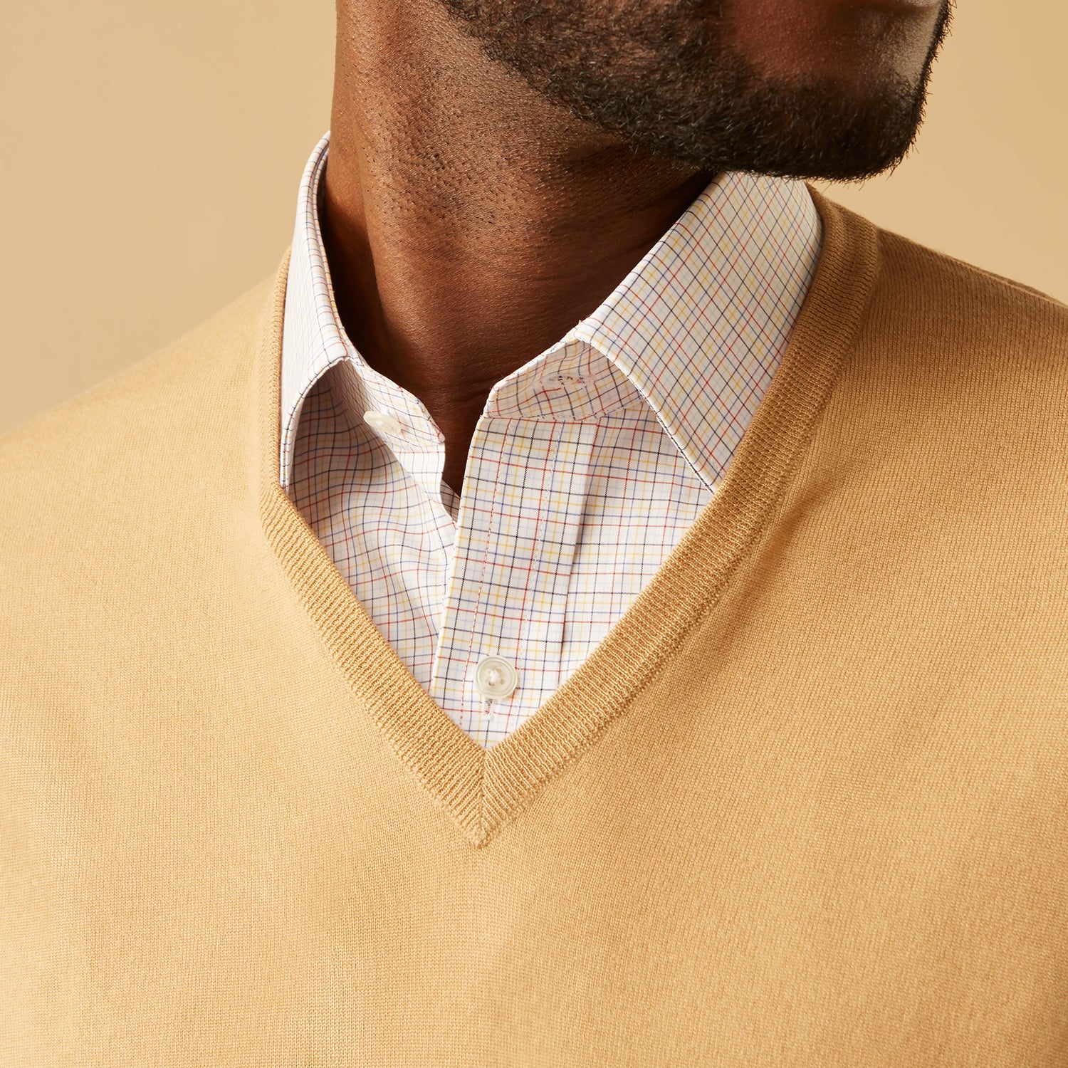 View 2 of product The Turnbull & Asser Camel V-Neck Merino Wool Jumper, with ribbed cuffs and a visible white neckline label, is neatly folded with one sleeve showing—an essential, versatile staple for any gentleman's wardrobe.
