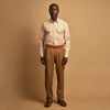 View 1 of product A man stands against a tan background wearing a Turnbull & Asser Orange Multi Stripe Regular Fit Shirt with T&A Collar and 3 Button Cuffs, paired with tan dress pants, brown belt, and brown shoes. He faces forward with a neutral expression.
