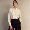 View 7 of product The Turnbull & Asser Turnbull and The Deck Cream Silk Romantic Shirt features long sleeves, a pointed collar, and elegant front ruffles, shown against a plain light gray background.
