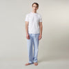 View 1 of product A man stands barefoot against a plain background, wearing a white short-sleeve T-shirt and Turnbull & Asser Blue Stripe Cotton Pyjama Trousers in a contemporary fit, looking straight ahead with a neutral expression.