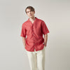 View 2 of product The Turnbull & Asser Crimson Delave Linen Holiday Fit Shirt features a solid brick-red hue, short sleeves, single chest pocket, and revere collar—perfect resort wear—shown laid flat on white.