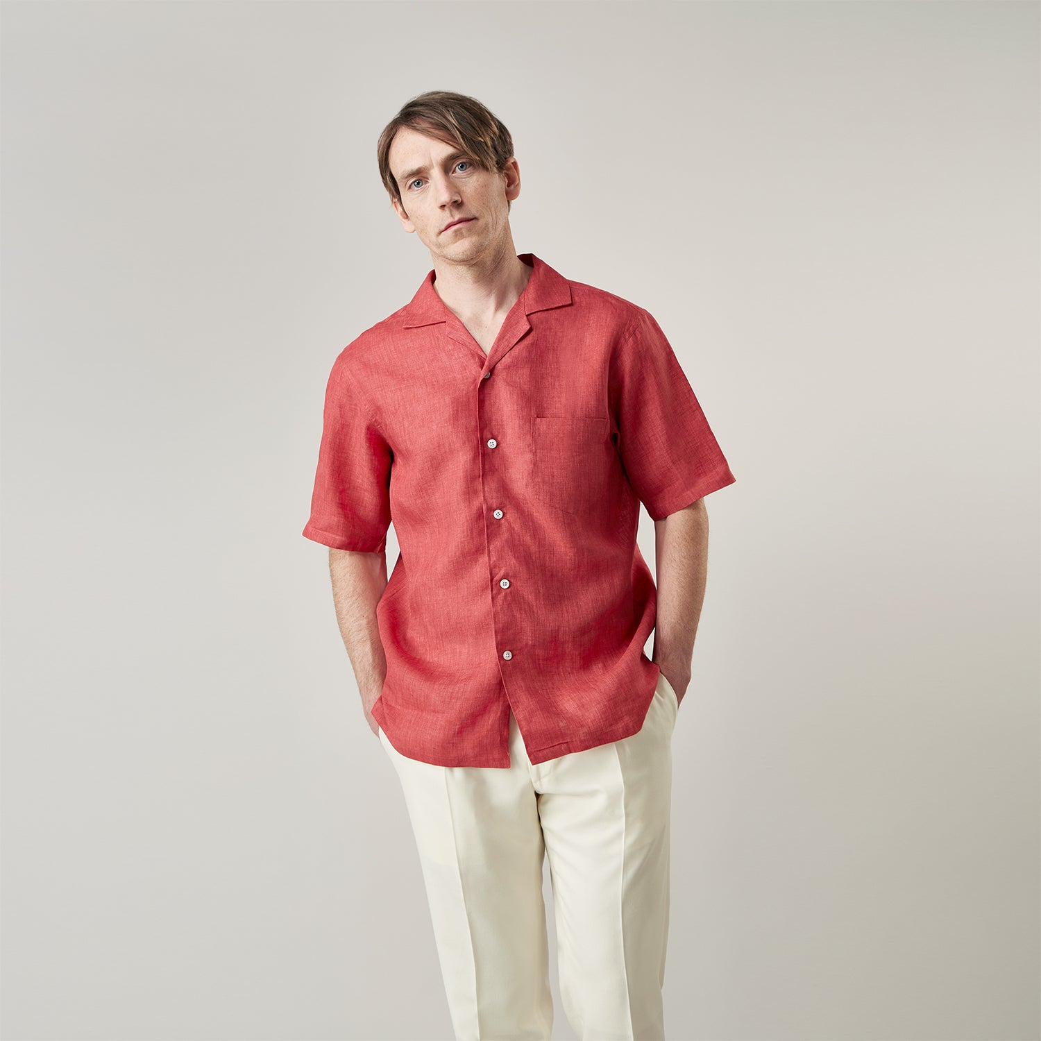 View 2 of product The Turnbull & Asser Crimson Delave Linen Holiday Fit Shirt features a solid brick-red hue, short sleeves, single chest pocket, and revere collar—perfect resort wear—shown laid flat on white.