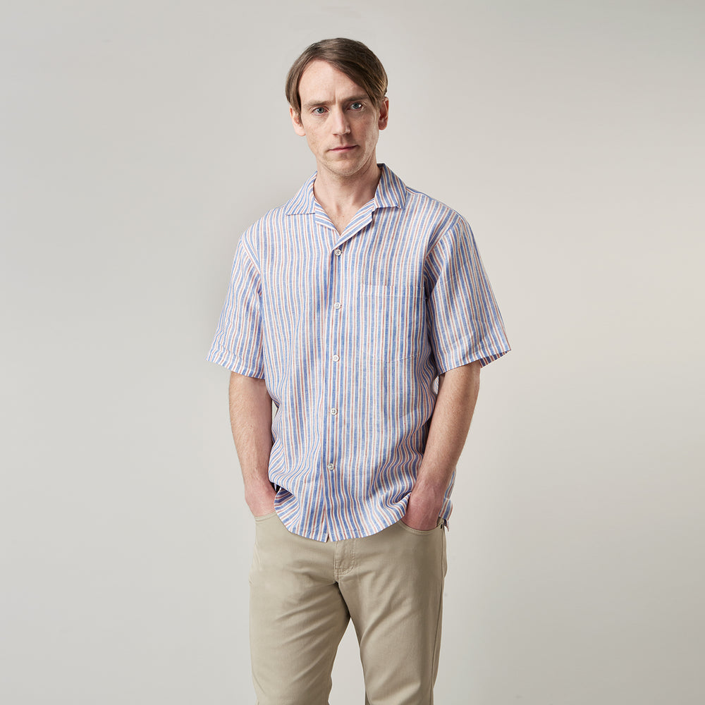 The Turnbull & Asser Blue and Red Linen Stripe Holiday Fit Shirt features a revere collar, relaxed fit, and short sleeves—perfect resort wear with vertical blue, white, and light red stripes.