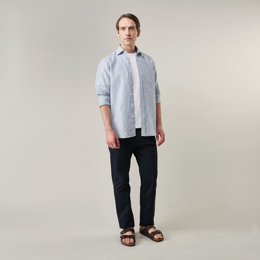 The Turnbull & Asser Sky Blue Linen Stripe Weekend Fit Shirt features blue and white vertical stripes, a Derby collar, and buttoned cuffs—ideal for pairing with classic cotton suits or other Weekend Fit shirts.