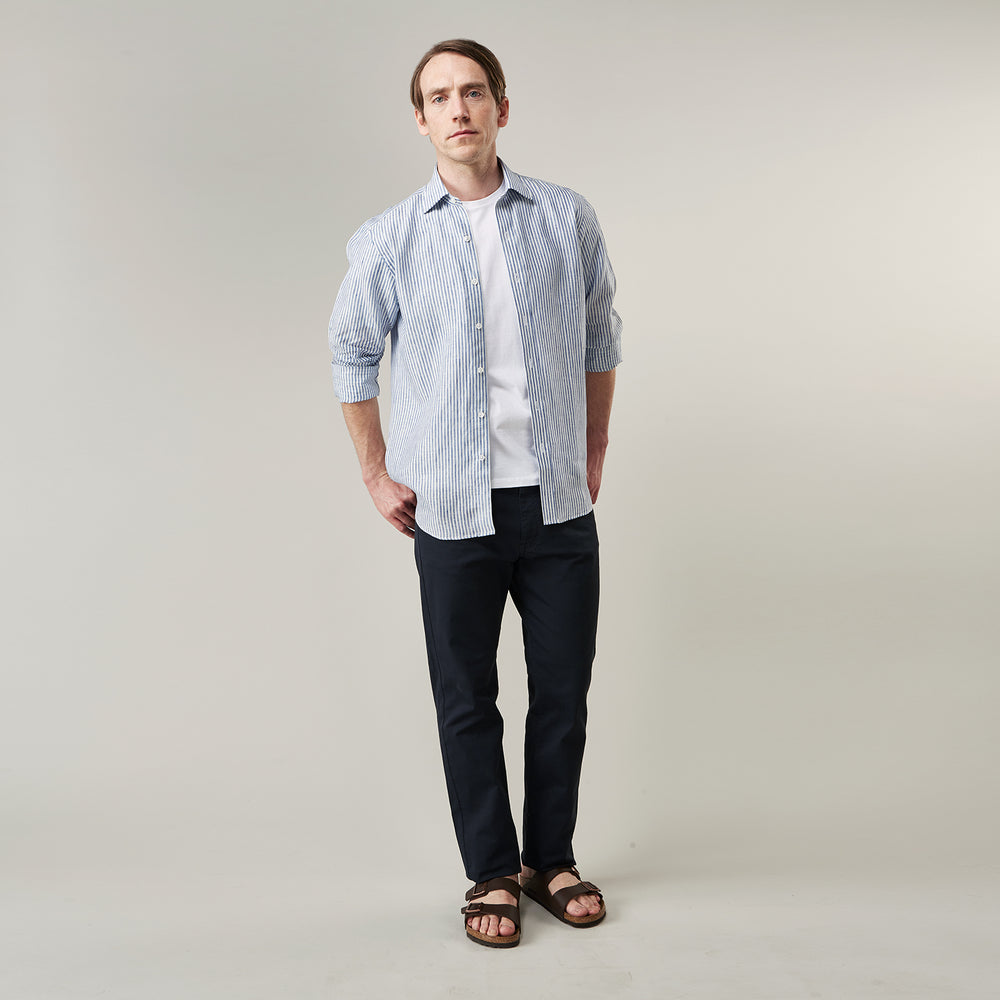 The Turnbull & Asser Sky Blue Linen Stripe Weekend Fit Shirt features blue and white vertical stripes, a Derby collar, and buttoned cuffs—ideal for pairing with classic cotton suits or other Weekend Fit shirts.