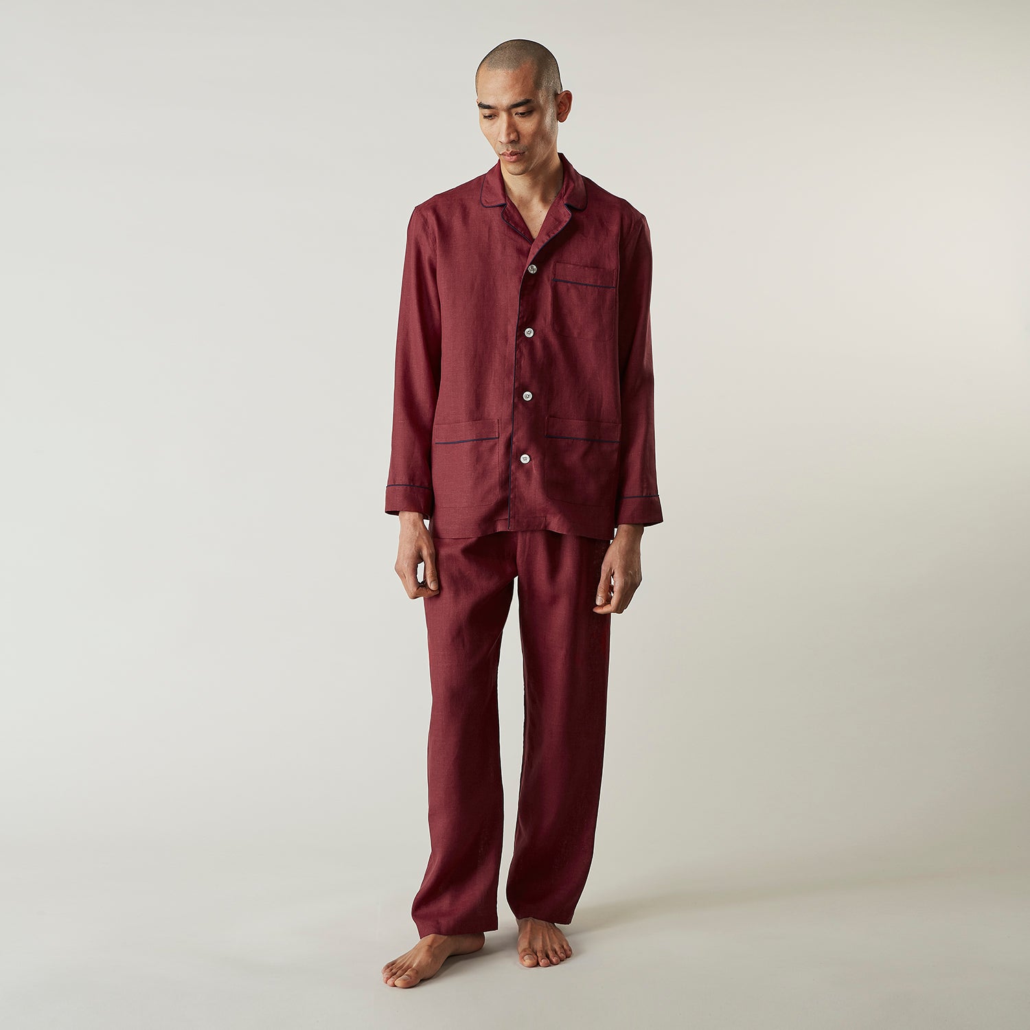 View 8 of product The Turnbull & Asser Burgundy Linen Modern Pyjama Set features a button-up, collared long-sleeve top with black piping and three pockets, plus matching pants with an elastic waistband.