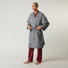 View 3 of product A barefoot person wears Turnbull & Asser's Navy Silk Chequered Kimono Gown with a belt over maroon pyjama sets, standing against a plain light background.