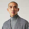 View 8 of product A barefoot person wears Turnbull & Asser's Navy Silk Chequered Kimono Gown with a belt over maroon pyjama sets, standing against a plain light background.