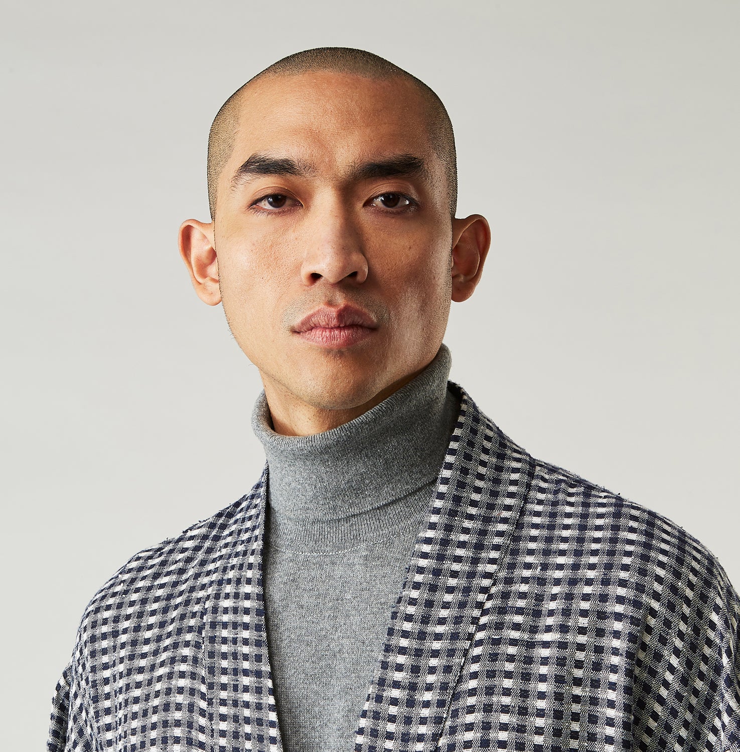 View 8 of product A barefoot person wears Turnbull & Asser's Navy Silk Chequered Kimono Gown with a belt over maroon pyjama sets, standing against a plain light background.
