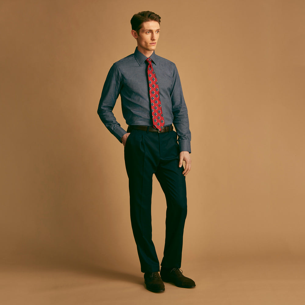 A rolled-up Red Shadow Spot Printed Silk Tie by Turnbull & Asser, showcasing large navy blue and white circular motifs, displayed on a plain white background.