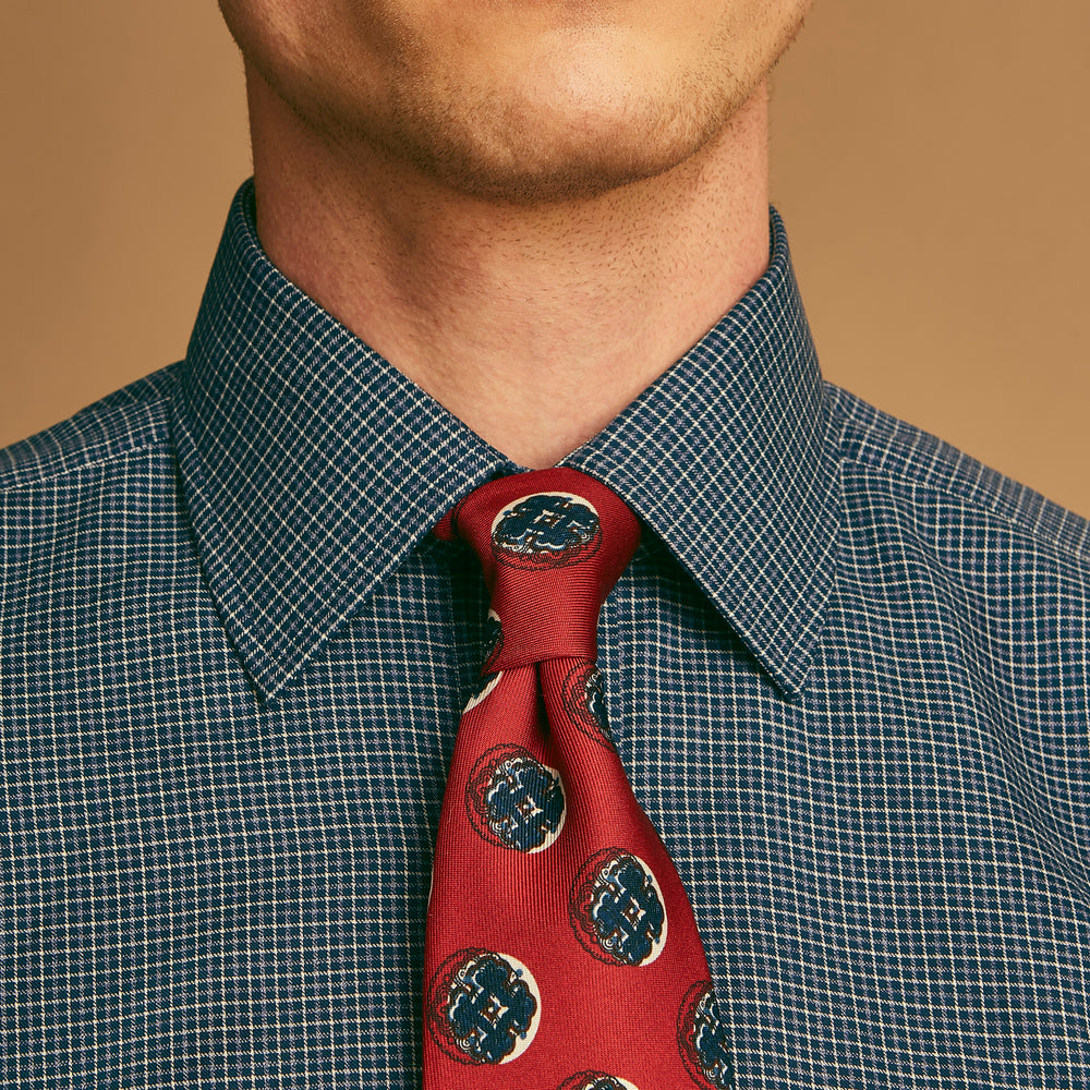 A rolled-up Red Shadow Spot Printed Silk Tie by Turnbull & Asser, showcasing large navy blue and white circular motifs, displayed on a plain white background.