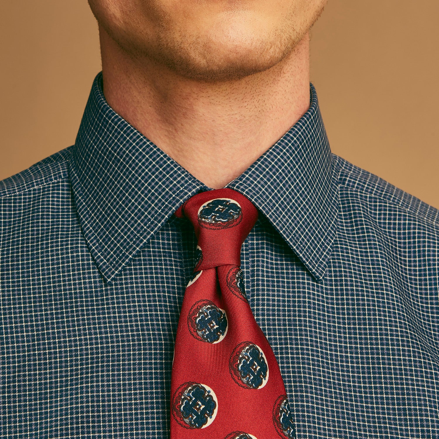 View 4 of product A rolled-up Red Shadow Spot Printed Silk Tie by Turnbull & Asser, showcasing large navy blue and white circular motifs, displayed on a plain white background.