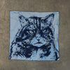 View 2 of product The Turnbull & Asser DANIEL PERKIN BLUE WILDCAT POCKET SQUARE features a blue-toned sketch of a tabby cat’s face with vivid eyes and fine fur detail on a pale blue background, finished with “DANISL” in the lower right corner.