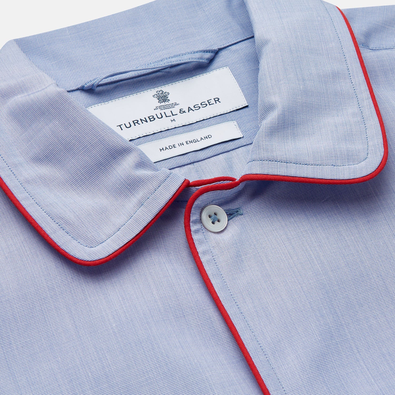 View 2 of product The Blue Piped End-on-End Cotton Nightshirt by Turnbull & Asser features light blue cotton, red piped accents, a chest pocket, high-low hem, and half-button placket—luxurious nightwear inspired by classic nightshirt style.