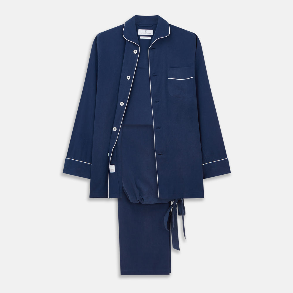 The Turnbull & Asser Navy Piped Silk Pyjama Set features a long-sleeve button-up top with a chest pocket and matching drawstring pants, laid flat on a white background for a luxurious look.