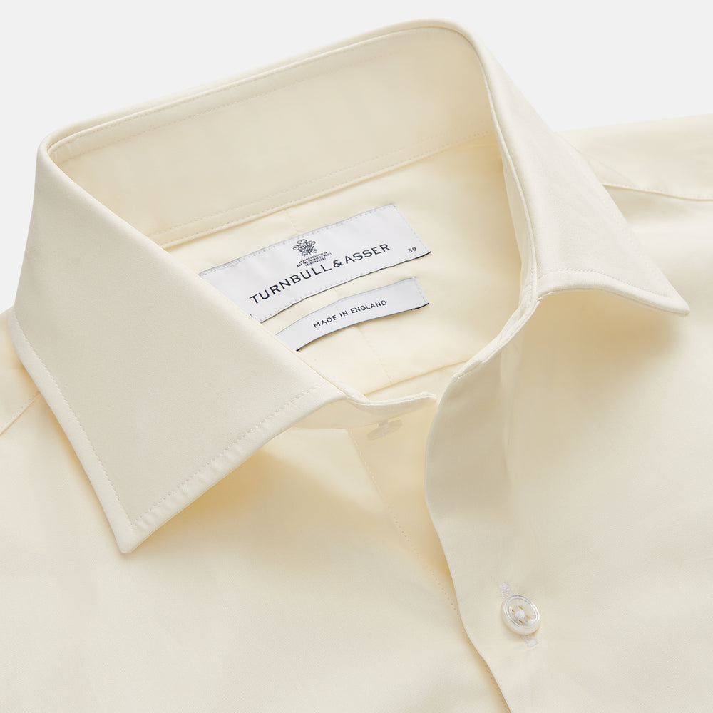 The Turnbull & Asser Tailored Fit Cream Cotton Shirt features a Kent collar and 3-button cuffs—a versatile minimalist choice, ideal on its own or paired with statement ties.