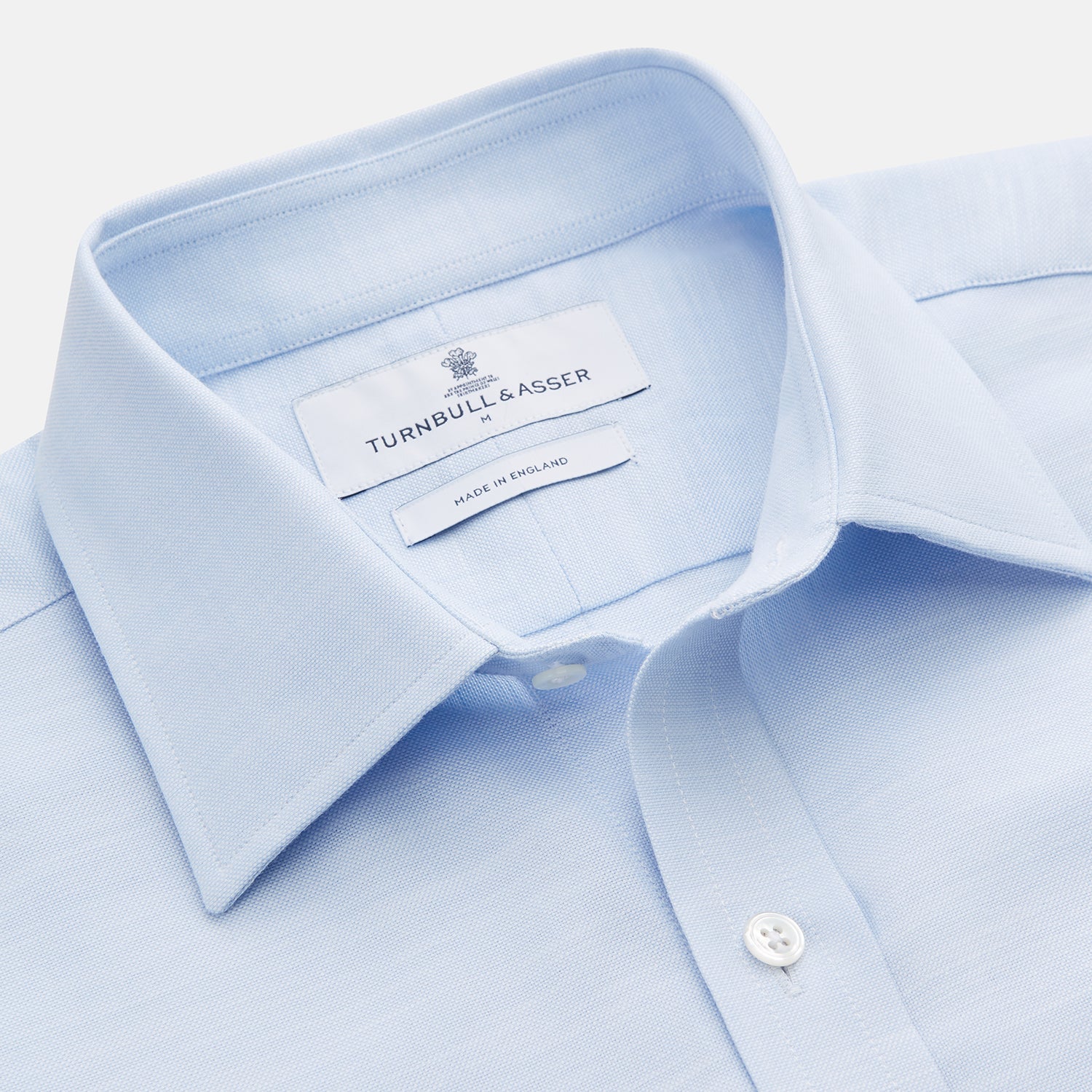 View 2 of product The Turnbull & Asser Plain Blue Weekend Fit Chambray Finch Shirt features a Derby collar, long sleeves, and a front chest pocket—shown laid flat on white—ideal for casual weekend wear.