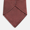View 4 of product The Turnbull & Asser Burgundy and White Diamond Silk Tie features a rolled-up design with a repeating white diamond pattern on burgundy, shown on a plain white background—a timeless accent for any office shirt.