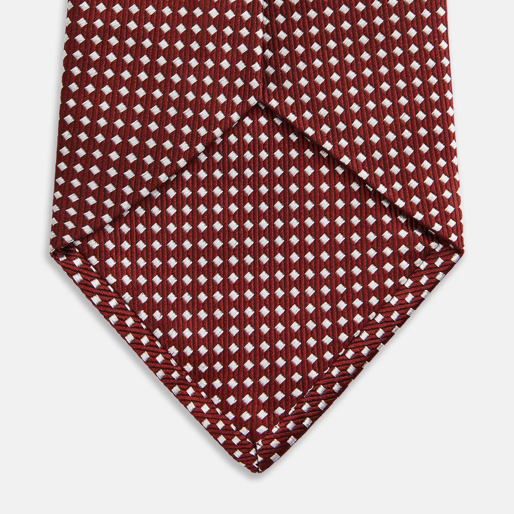 The Turnbull & Asser Burgundy and White Diamond Silk Tie features a rolled-up design with a repeating white diamond pattern on burgundy, shown on a plain white background—a timeless accent for any office shirt.