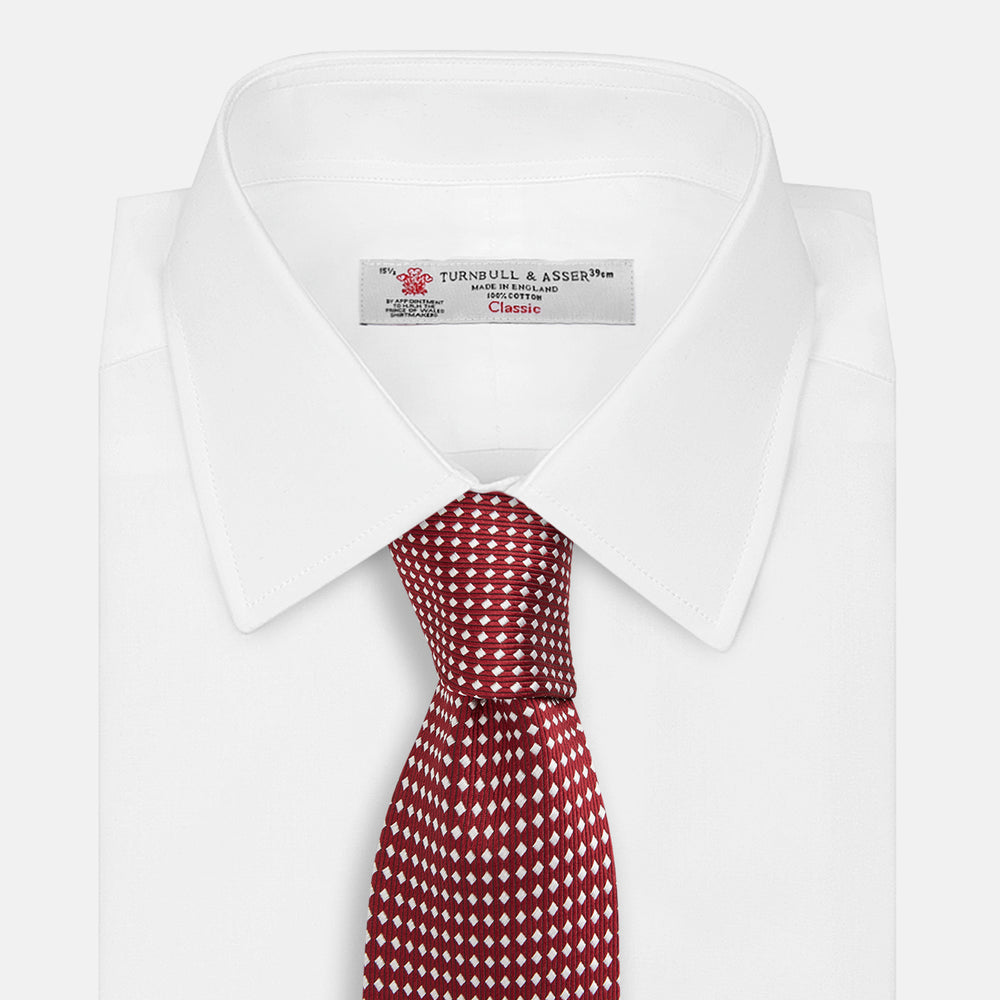 The Turnbull & Asser Burgundy and White Diamond Silk Tie features a rolled-up design with a repeating white diamond pattern on burgundy, shown on a plain white background—a timeless accent for any office shirt.