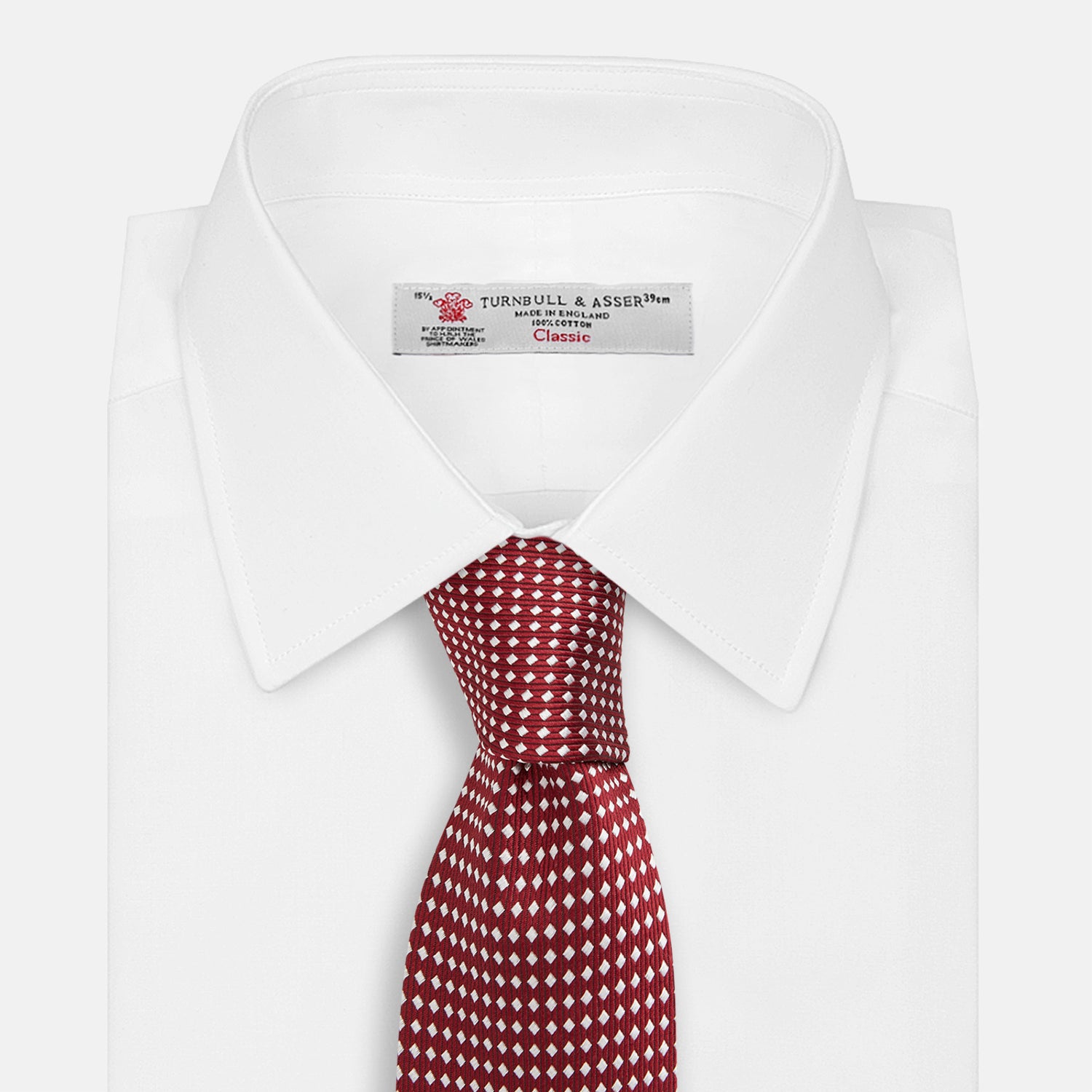 View 2 of product The Turnbull & Asser Burgundy and White Diamond Silk Tie features a rolled-up design with a repeating white diamond pattern on burgundy, shown on a plain white background—a timeless accent for any office shirt.