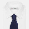 View 2 of product The Long Navy Herringbone Silk Tie by Turnbull & Asser is shown rolled up on a plain white background, highlighting its subtle herringbone weave and luxurious silk fabric.